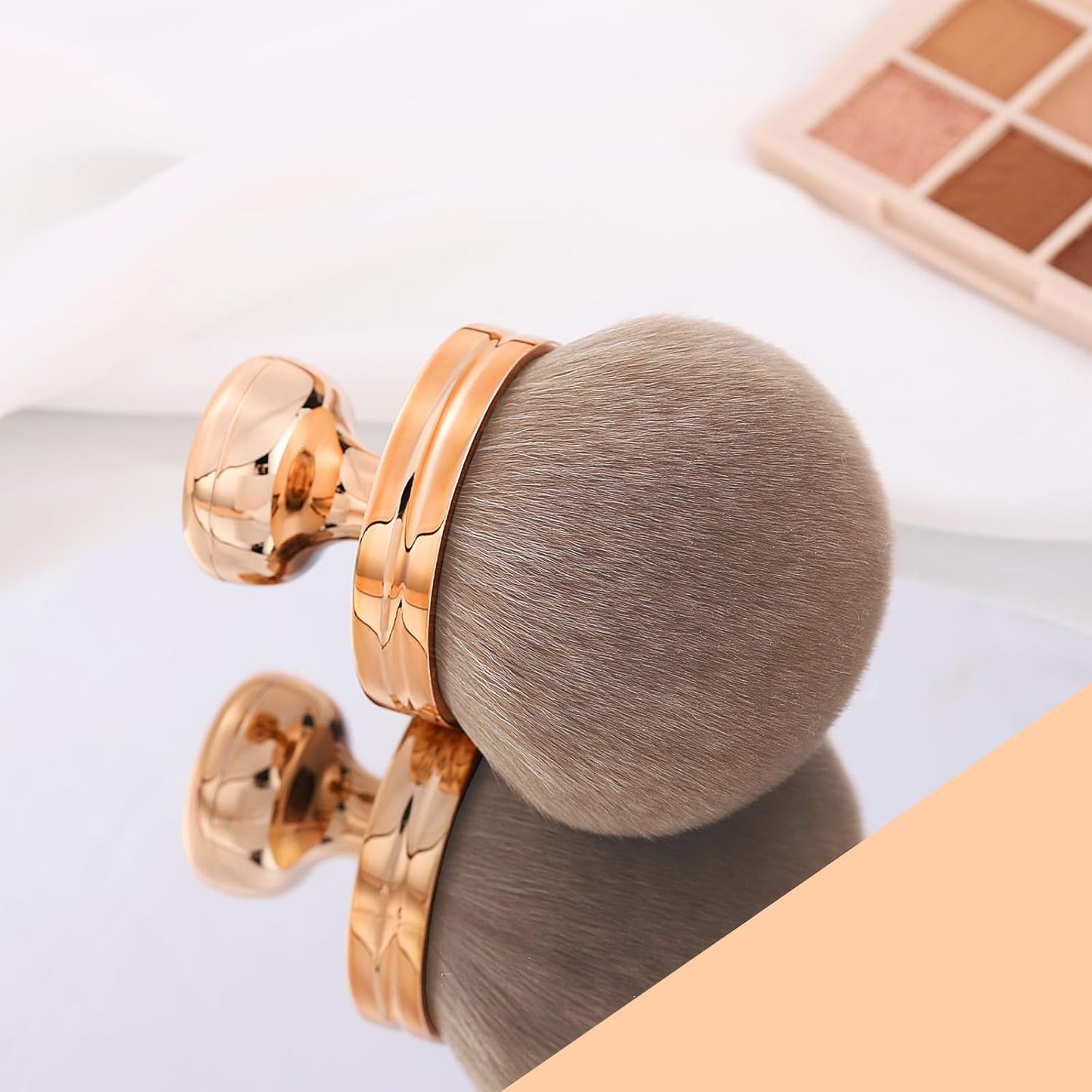 Wide-Head Foundation & Bronzer Brush on a reflective surface with a soft, round brush head.